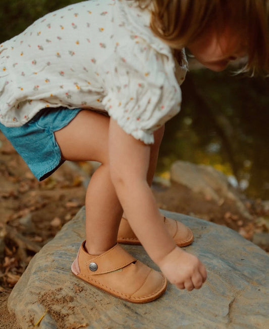 Child wearing barefoot shoes with a flexible sole and wide toe box, allowing natural movement and balance during play.