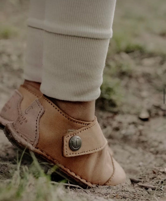 Toddler in flexible barefoot shoes walking on grass