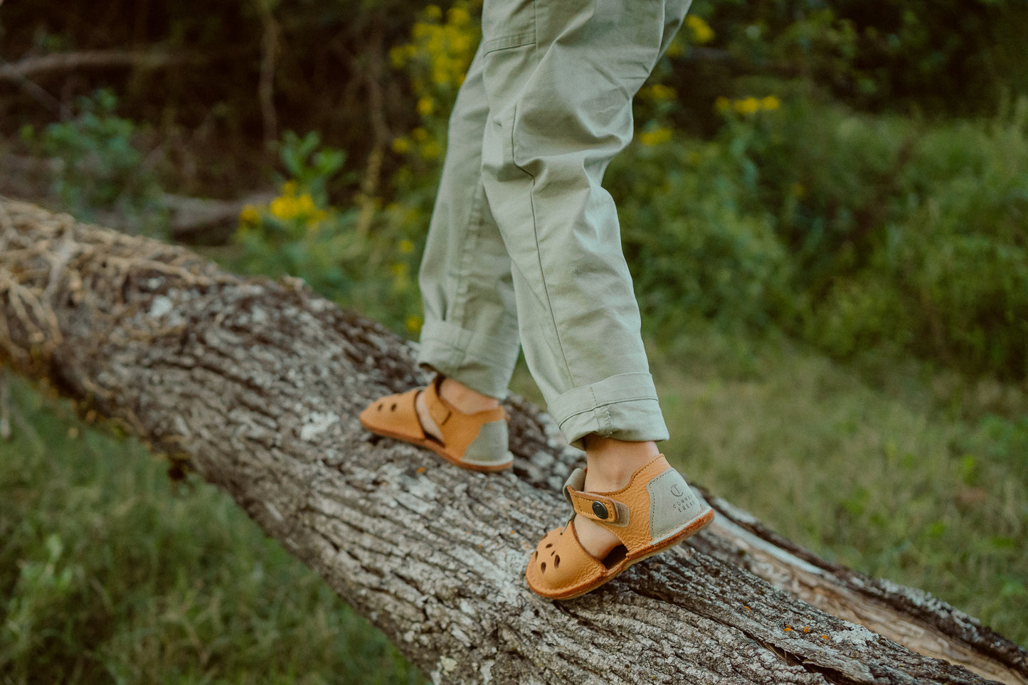 Child walking on log wearing barefoot sandals outdoors