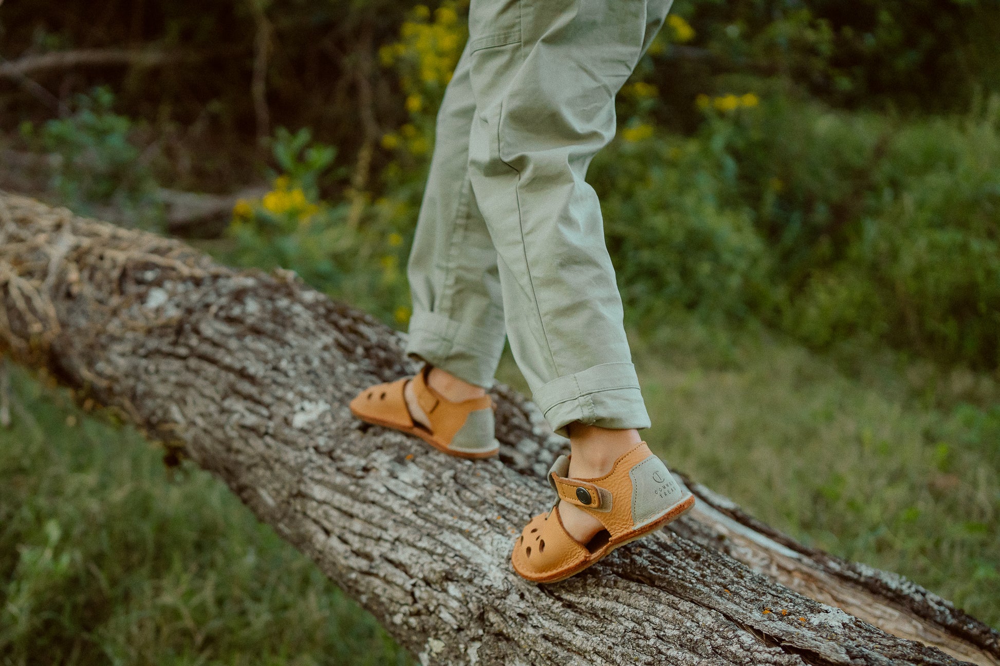 Child walking on log wearing barefoot sandals outdoors