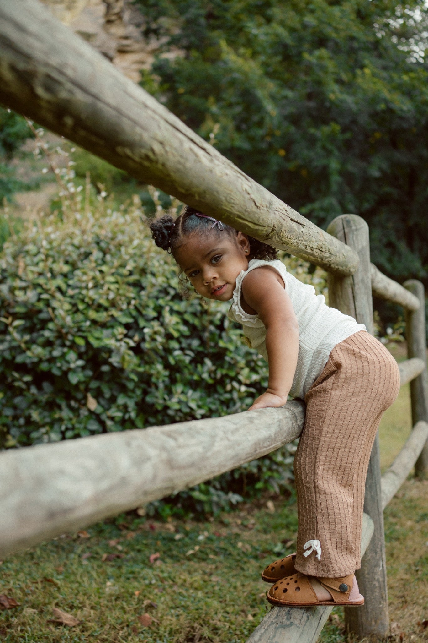 Toddler climbing fence wearing flexible leather barefoot sandals