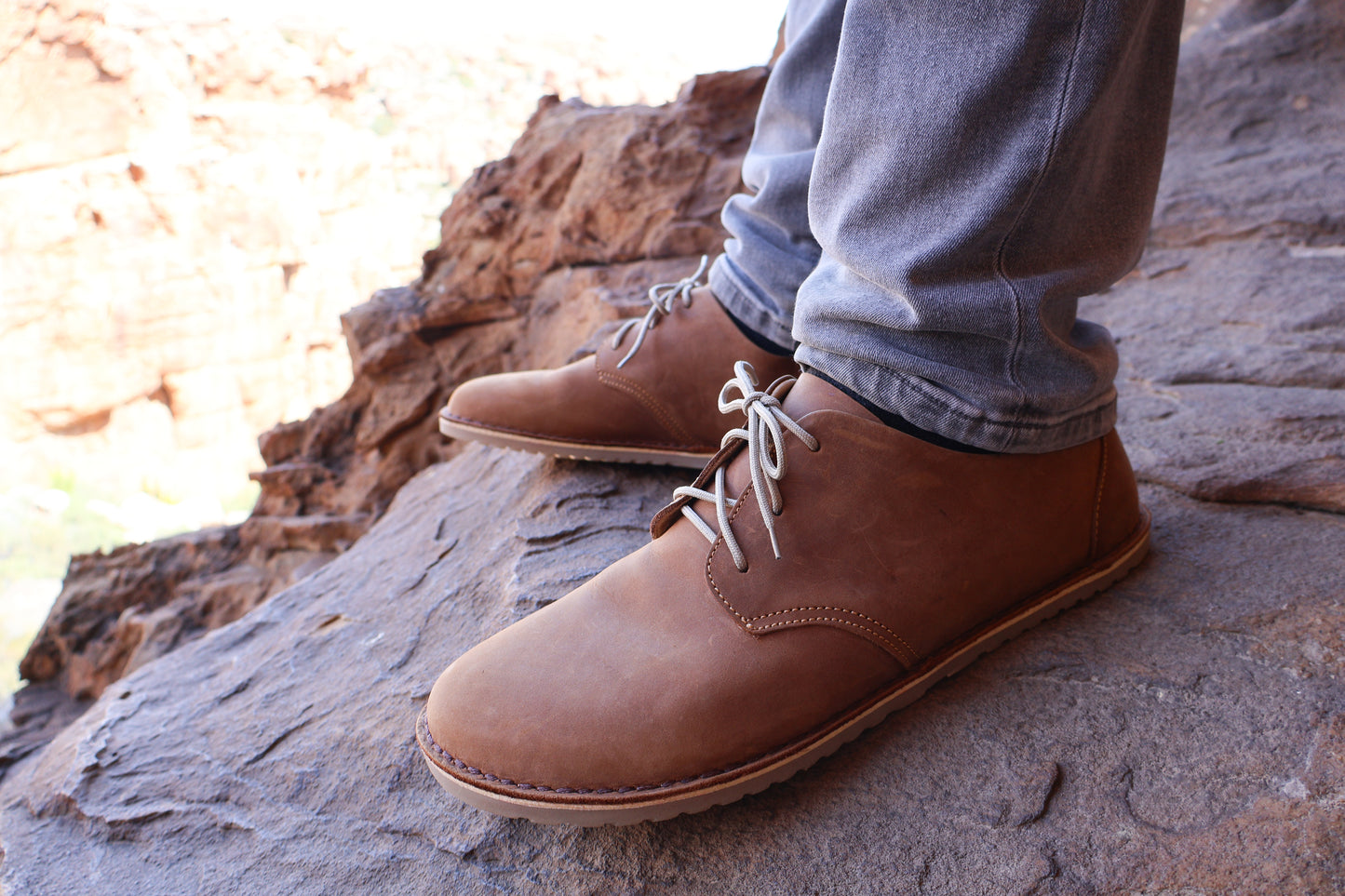 Close side view of Common Tread Traversa men’s barefoot leather shoe outdoors on rock terrain
