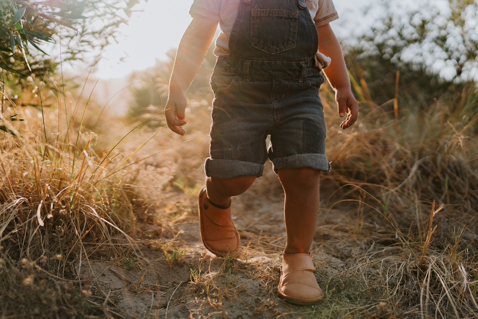 Toddler walking along a sunlit path wearing Common Tread Evergreen barefoot shoes