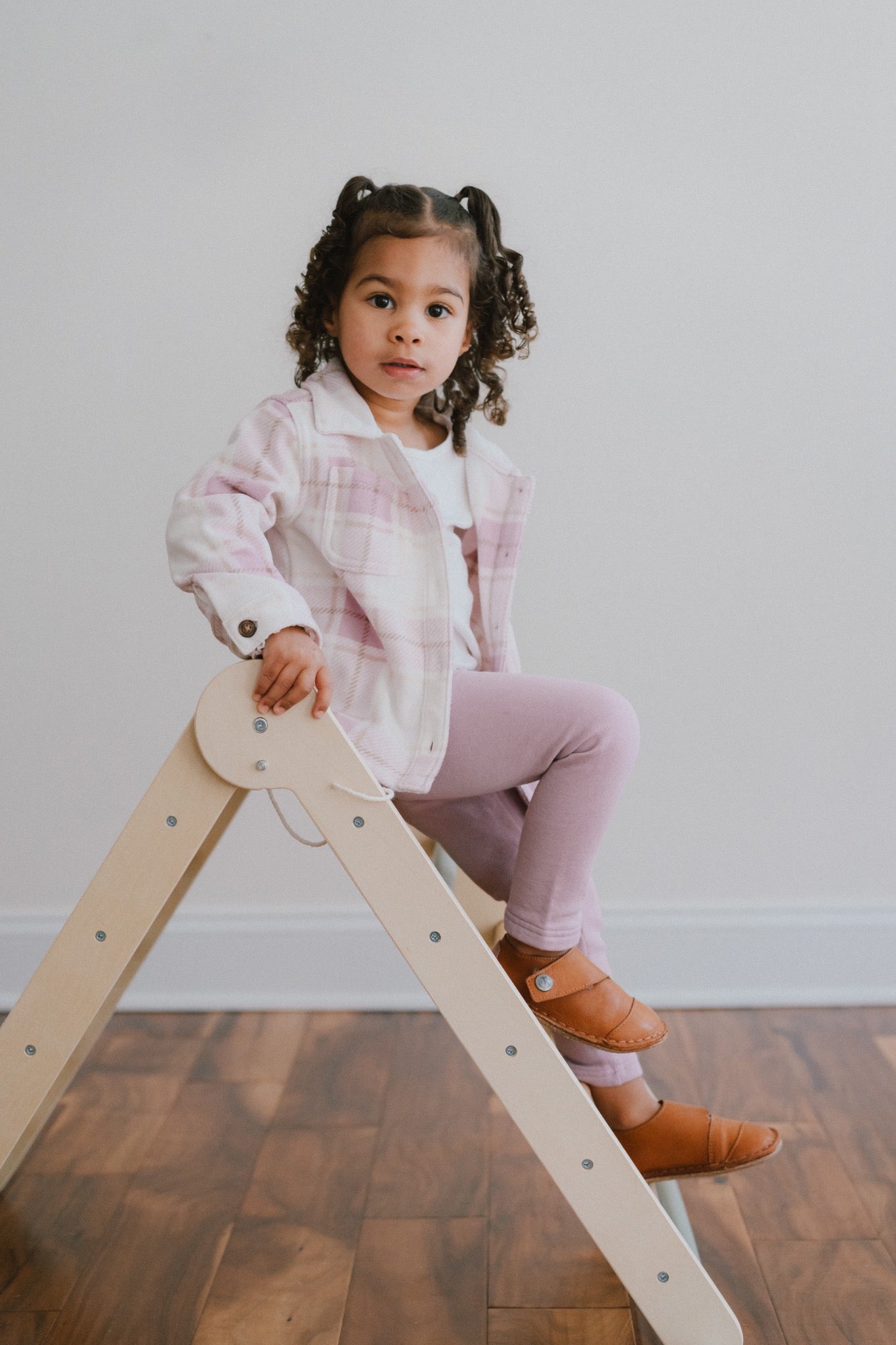 Child sitting indoors wearing Common Tread Evergreen leather barefoot shoes