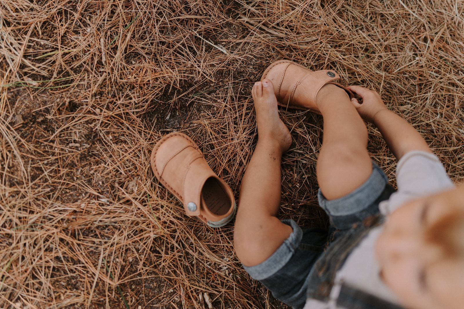 Child putting on Common Tread Evergreen shoes with easy adjustable velcro closure