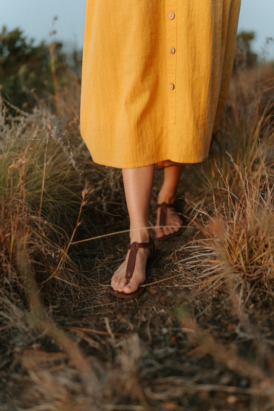 Woman walking through grass wearing Sierra women’s leather barefoot sandals