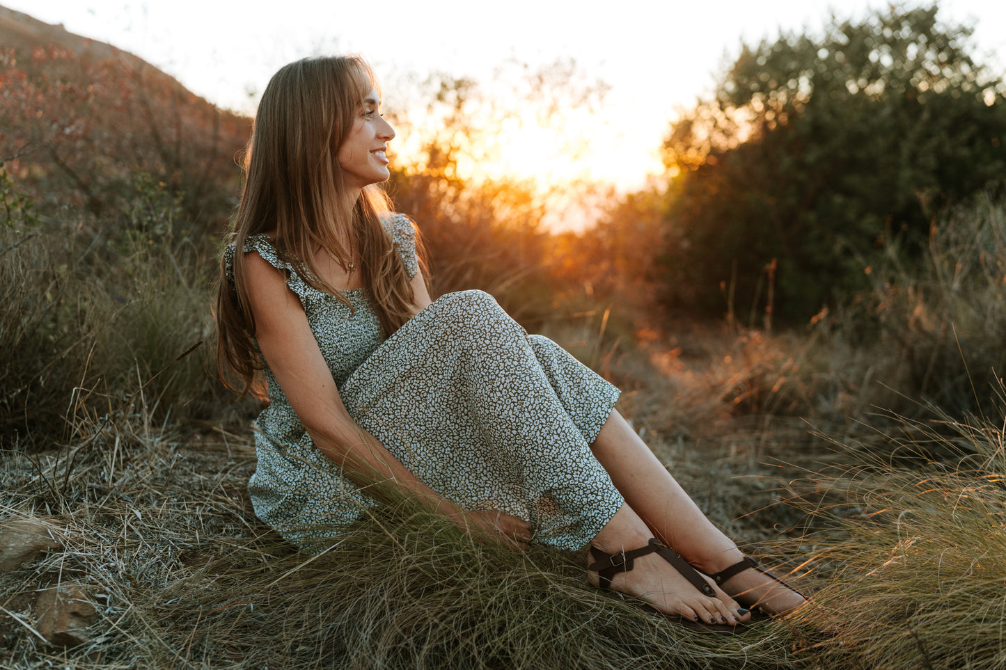 Woman wearing Sierra women’s leather barefoot sandals while sitting outdoors at sunset
