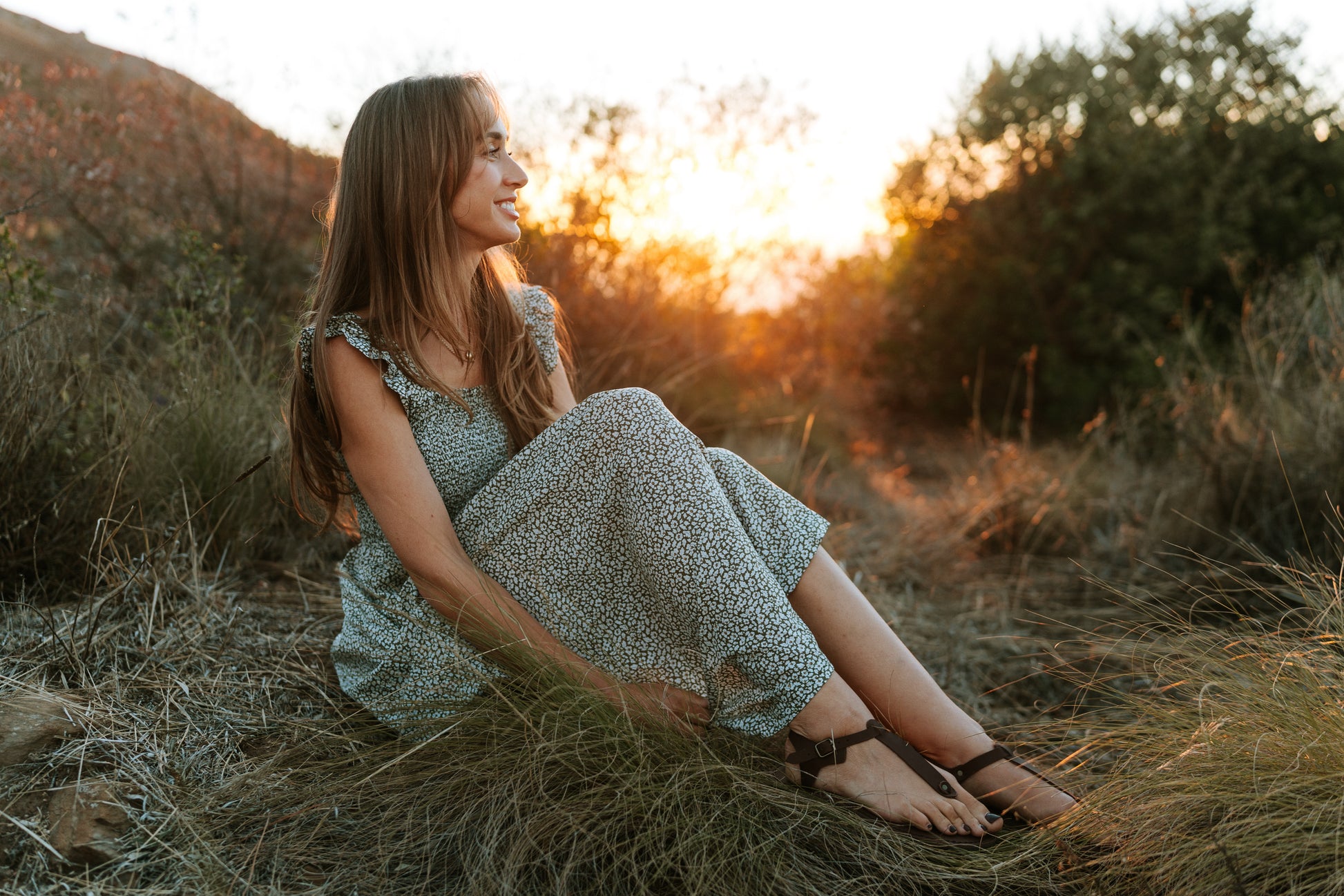 Woman wearing Sierra women’s leather barefoot sandals while sitting outdoors at sunset
